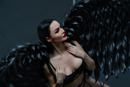 Enchanting beauty in black lingerie with striking wings posing gracefullyの写真素材