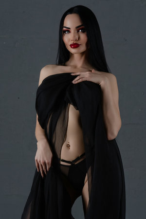 Elegant woman in black lingerie with flowing sheer fabric posing gracefullyの写真素材