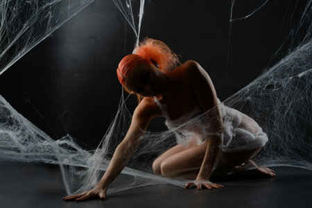 Red-haired woman entangled in a net trap surrounded by synthetic webbingの写真素材
