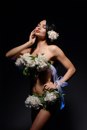 Brunette beauty adorned with flowers in artistic poseの写真素材