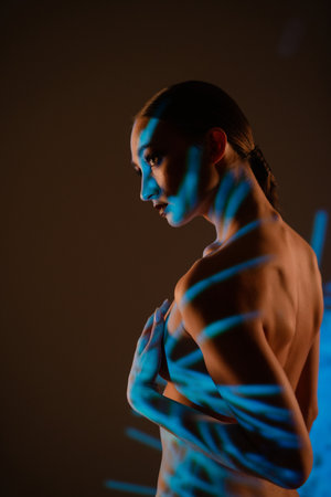 Woman poses with projected light creating shadows on her bodyの写真素材