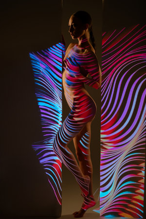 Woman interacting with colorful light projections in a creative displayの写真素材