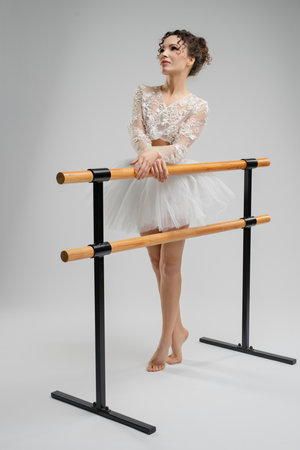 Elegant ballet dancer poses gracefully near a barre under soft lightingの写真素材