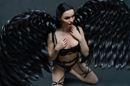 Elegance and allure of a woman in lingerie with striking black wingsの写真素材