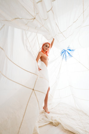 Woman With Pink Hair Posing Inside a White Parachuteの写真素材