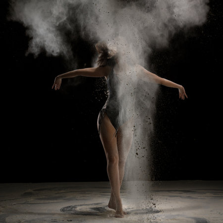 Dynamic dance movement captured with a cloud of powder in dark settingの写真素材