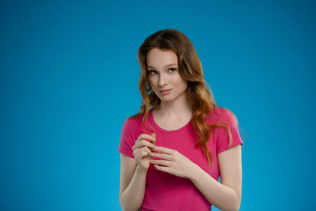 Woman posing with a thoughtful expression in a studio setting against a vibrant blue backgroundの写真素材