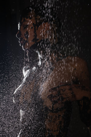 Woman showcasing intricate body art while standing under cascading waterの写真素材