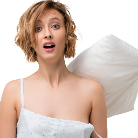 Surprised woman holding a pillow in a playful indoor settingの写真素材