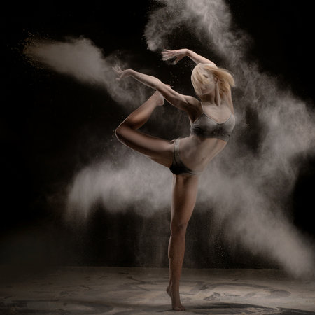 Dancer creates dynamic movement with flour in dramatic lightingの写真素材