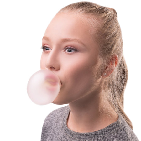 Girl blowing a bubble with chewing gum indoors in a bright settingの写真素材