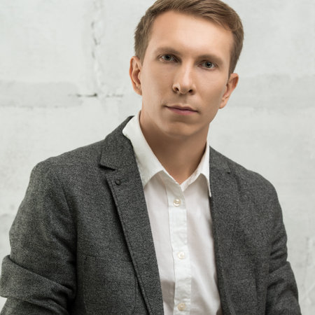 Young businessman in formal attire posing confidently against a plain backdropの写真素材