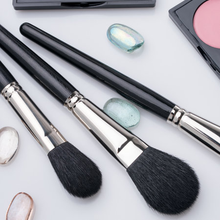 Makeup brushes arranged with gemstones on a clean surfaceの写真素材