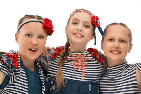 Three girls in matching outfits with red flowers smile cheerfully together