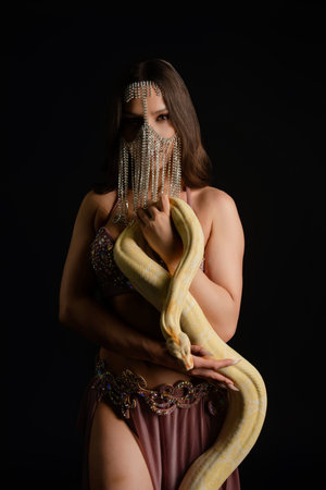Woman poses elegantly in studio while playfully interacting with a snake