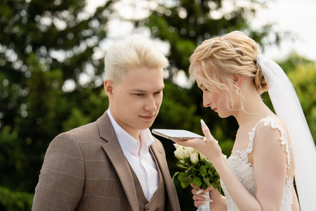 Bride and groom sharing a moment during wedding ceremony in a gardenの写真素材