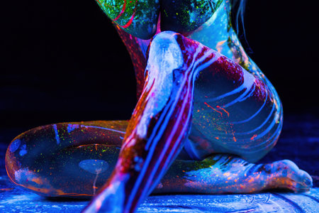 Womans body covered with fluorescent paint under black lightの写真素材