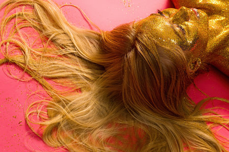 Golden glitter art with long hair on bright pink during a session