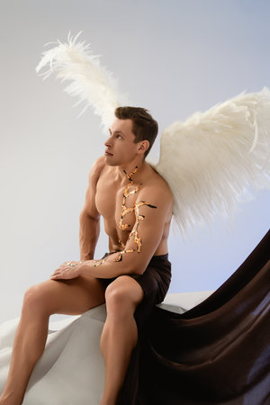 Model posing with feathered wings and artistic body paint in studio setting