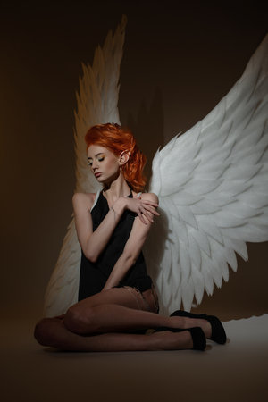 Elegant woman with angel wings poses gracefully in studioの写真素材