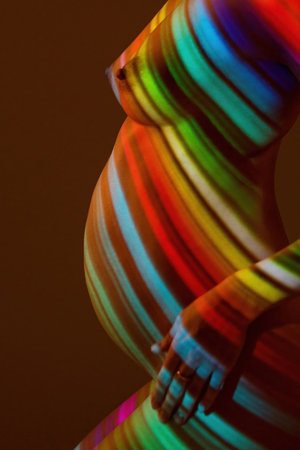 Expecting mother displays beautiful colorful light pattern on her bodyの写真素材