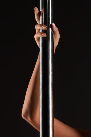Womans arm gripping a metal pole on dark background in studioの写真素材