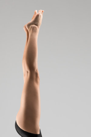 Leg extended high against a neutral background showcasing graceful movement and formの写真素材