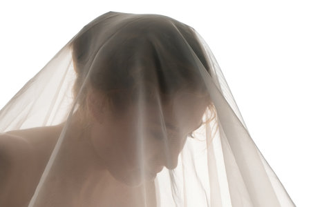 Woman in sheer veil looking down with soft focus on her delicate featuresの写真素材