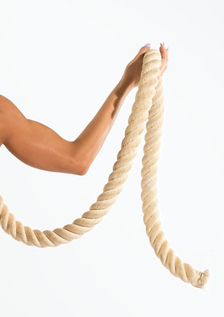 Person holding thick beige rope for workout on bright white backgroundの写真素材