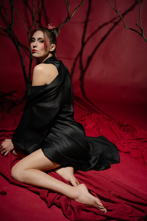 Woman in traditional Japanese dress poses elegantly in a studio with red backdropの写真素材