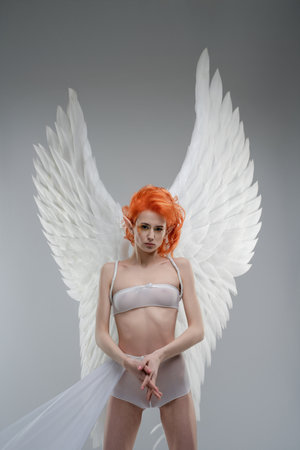 Elegant woman with angel wings poses in studio settingの写真素材