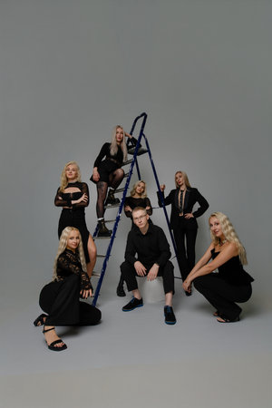 Group of stylish people posing creatively around a ladder for a photoshoot in a studioの写真素材