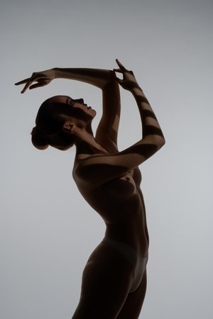 Woman posing gracefully in artistic silhouette against a minimalist backgroundの写真素材