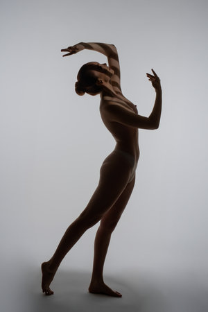 Elegant silhouette of a woman striking a graceful pose in a studio settingの写真素材
