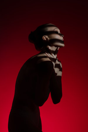 Woman poses gracefully against a bold red backdropの写真素材