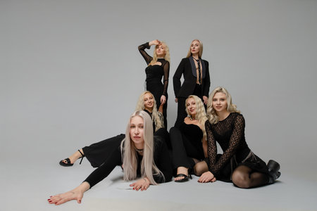 Group of women in black outfits posing creatively in a studio setting for fashion photographyの写真素材