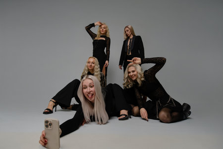 Group of friends posing for a fun selfie in stylish outfits against a plain backgroundの写真素材