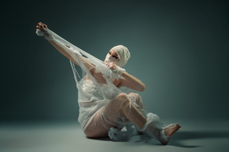 Conceptual art of a person wrapped in bandages struggling to break free from confinement.