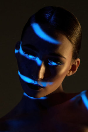 Woman face with blue light on skin in studio at night