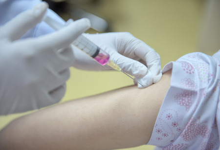 Soft focus nurses are vaccinations to patients using the syringe.Doctor vaccinating women in hospital.Are treated by the use of sterile injectable upper arm. injectionの写真素材