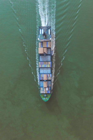 Container ship in export and import business and logistics. Shipping cargo to harbor by crane. Water transport International. Aerial viewの写真素材