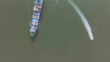 Container ship in export and import business and logistics. Shipping cargo to harbor by crane. Water transport International. Aerial viewの写真素材