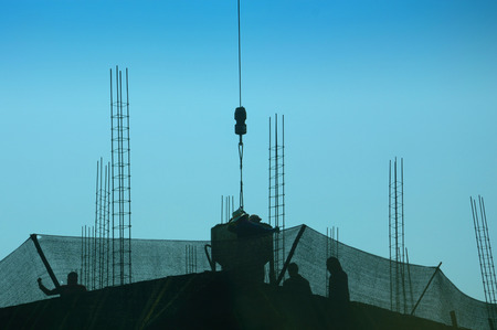 silhouette of construction workers on scaffolding working under the blue sky