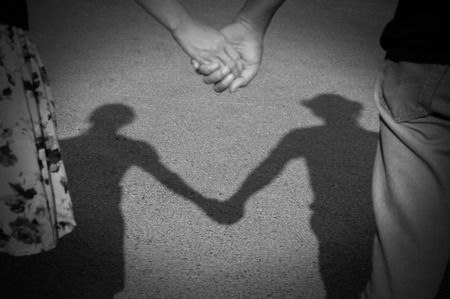 shadow of lover couple holding hand reflected on a pavement in the sunset lightの写真素材