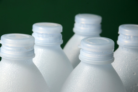 rows of white plastic bottles isolated on green background の写真素材