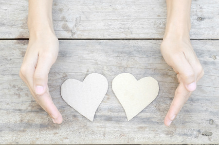 paper heart with woman hand on wood backgroundの写真素材