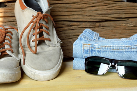 jeans sneakers and sunglasses on wooden backgroundの写真素材