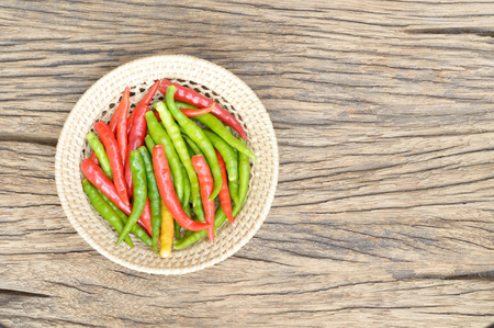 chilli in wicker basket on wooden background, guinea-pepperの写真素材