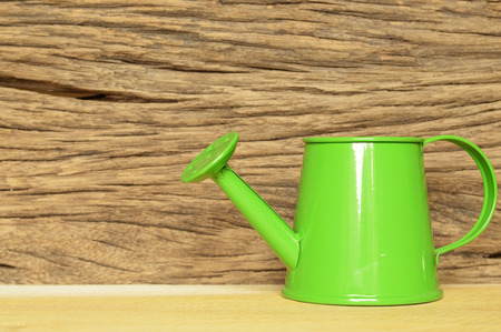 green watering pot on old wooden tableの写真素材