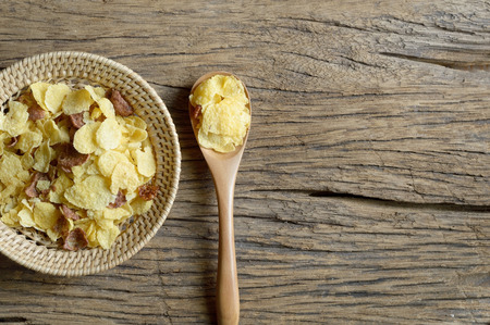 cornflakes in wicker basket on wooden background